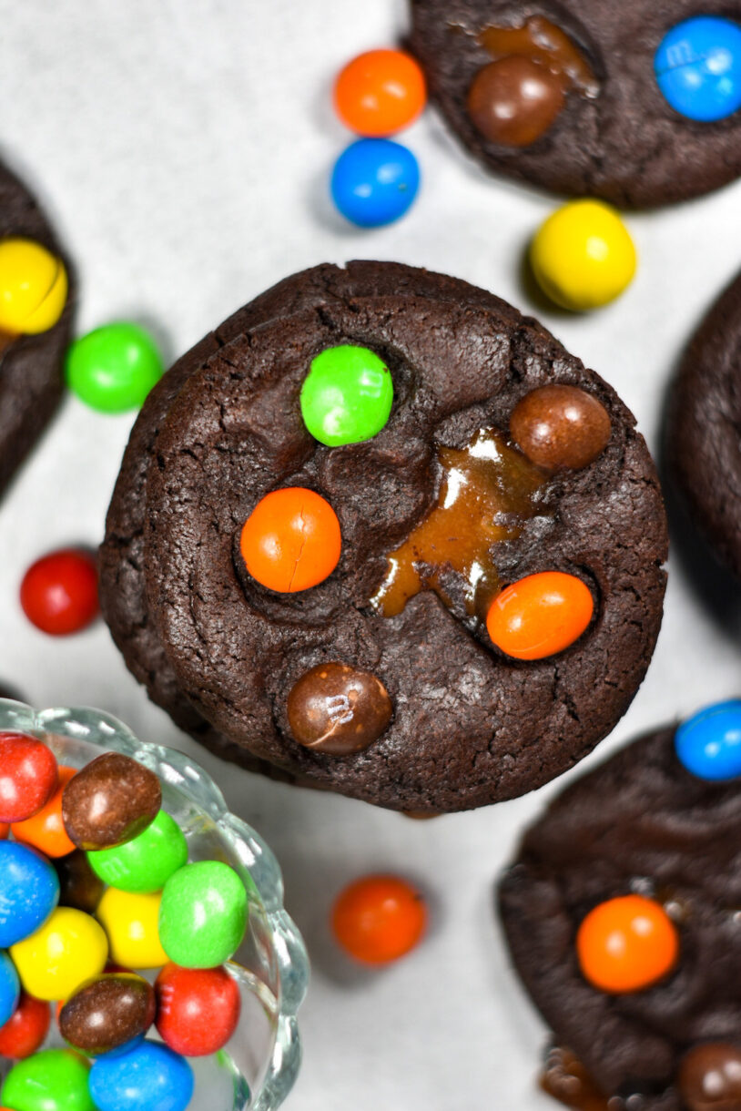 Caramel M&M Cookies and a bowl of M&Ms on white surface