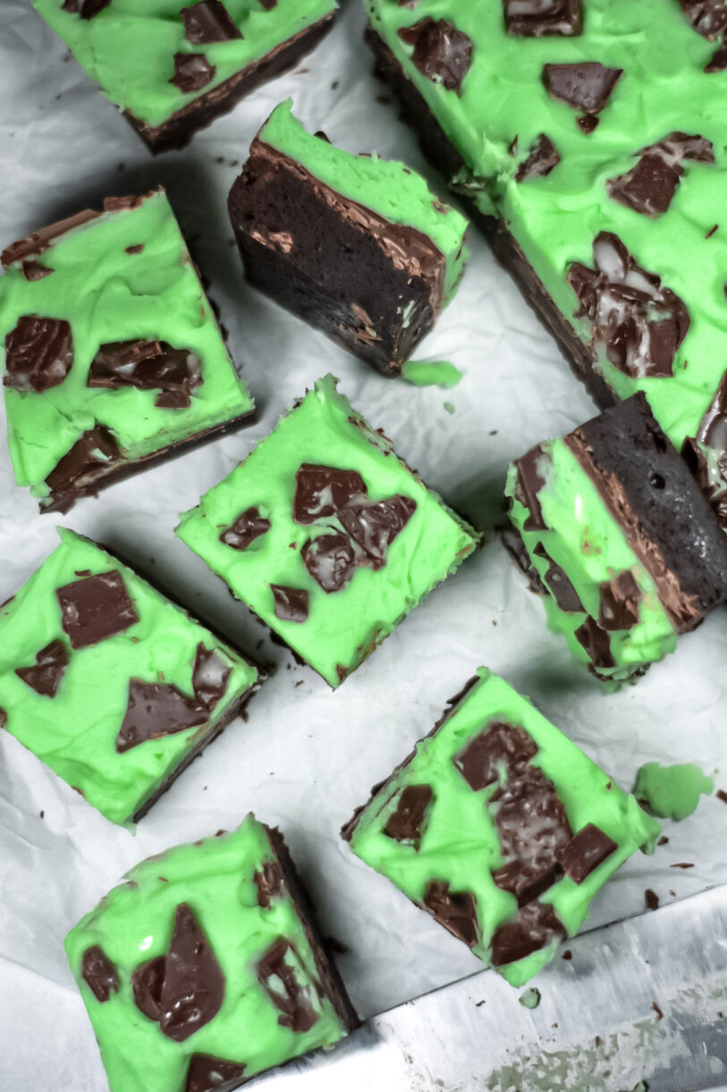 Brownies with mint green buttercream, on a white surface