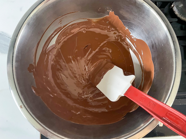 A bowl of melted chocolate with a spatula