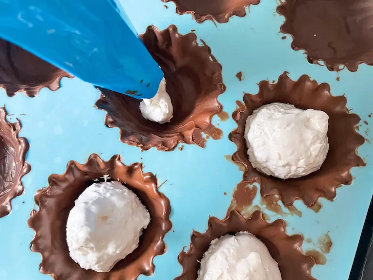 Piping bag piping marshmallow into chocolate cups