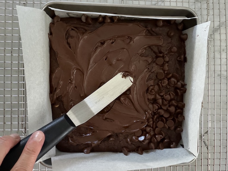 small palette knife spreading chocolate over brownies