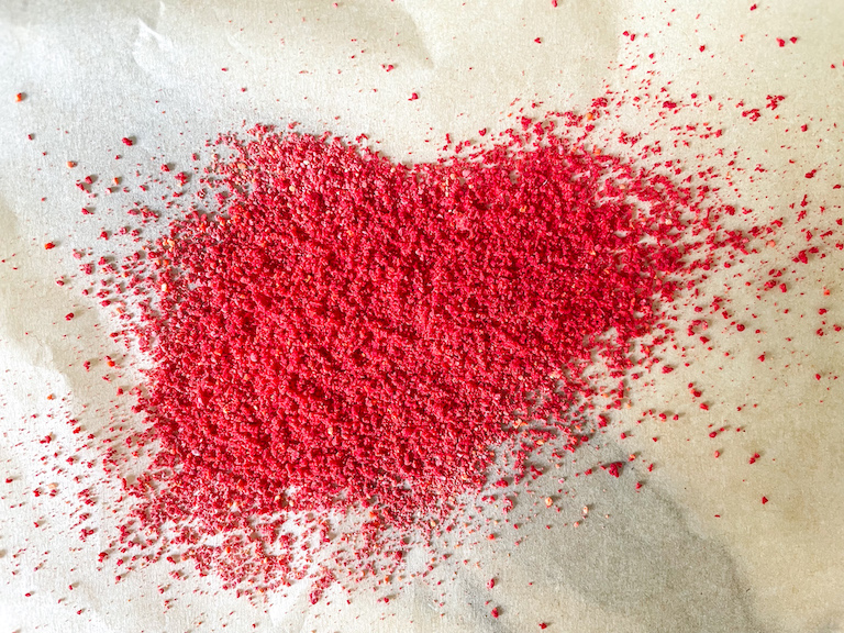 Red tinted sugar scattered on a sheet of parchment