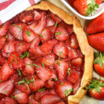 Looking down at a strawberry galette surrounded by fresh berries