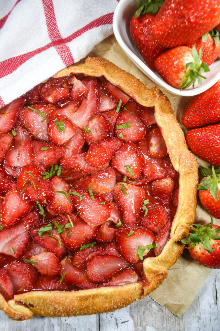 Looking down at a strawberry galette surrounded by fresh berries