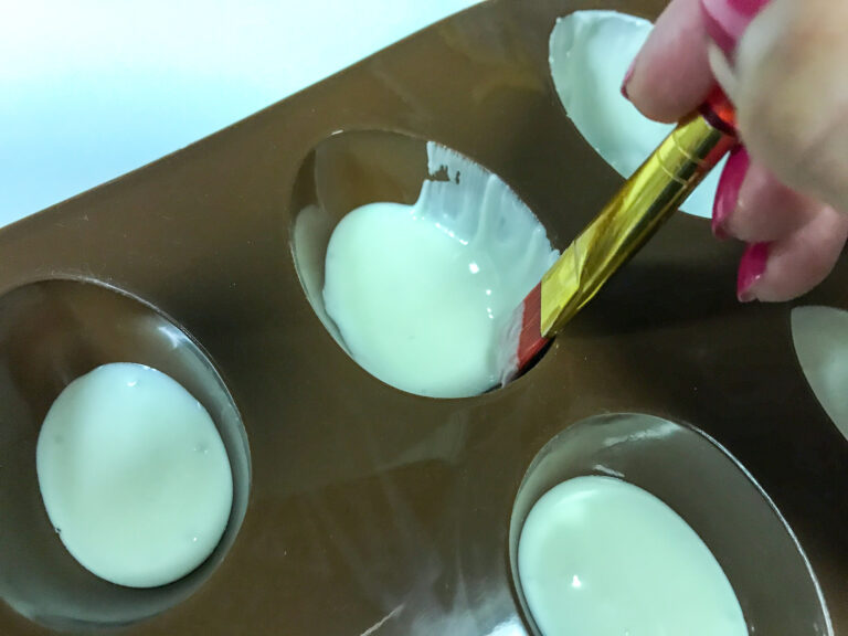Brushing white chocolate into egg mold