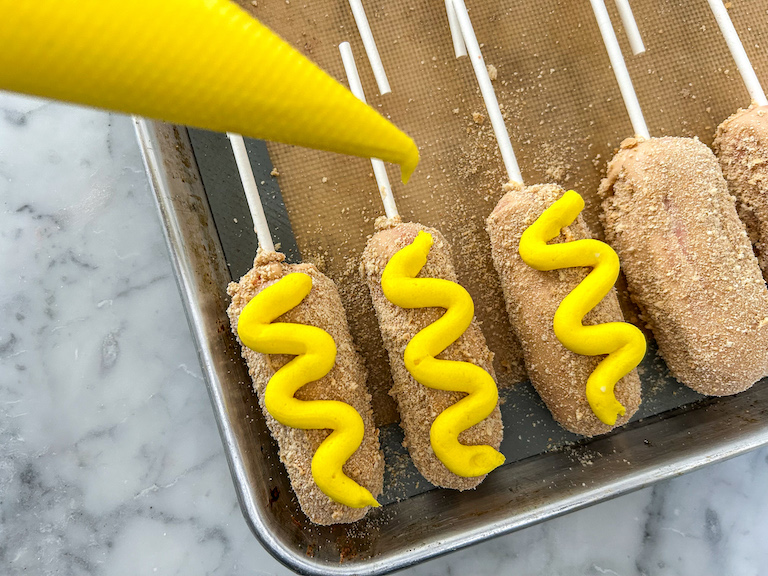 Piping bag decorating corn dog cake pops