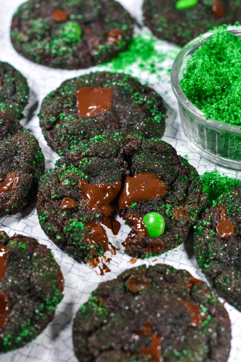 mint chocolate cookies with a bowl of green sugar, on a white surface
