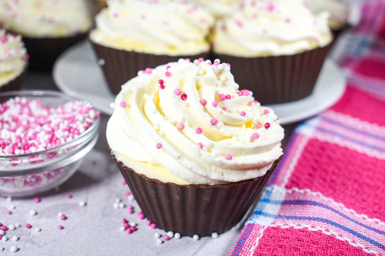 Ice cream cupcake with a pink tea towel and bowl of sprinkles