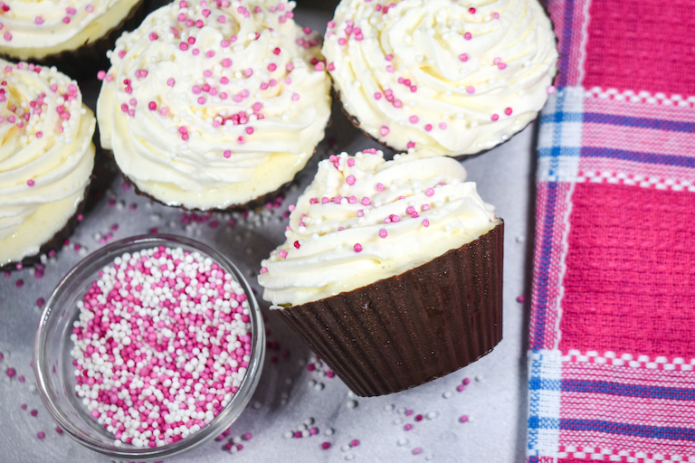 Ice cream cupcake in a chocolate cupcake cup, with bowl of sprinkles and pink plaid towel