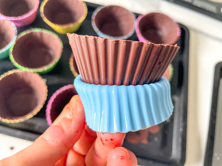 Hand popping a chocolate cupcake cup from a silicone liner