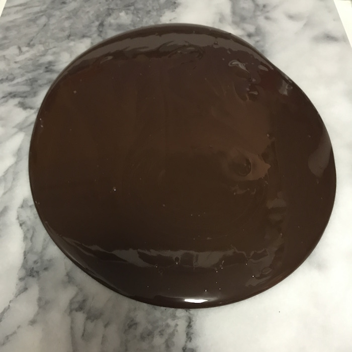 A large pool of melted chocolate on a marble surface