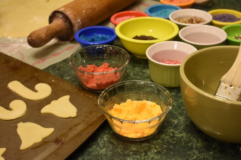 Sand tarts on a tray, a rolling pin, dough, and bowls of colored sugar
