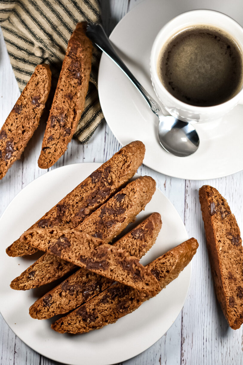 Espresso Chocolate Chip Biscotti, white plates, a cup of coffee, and a spoon