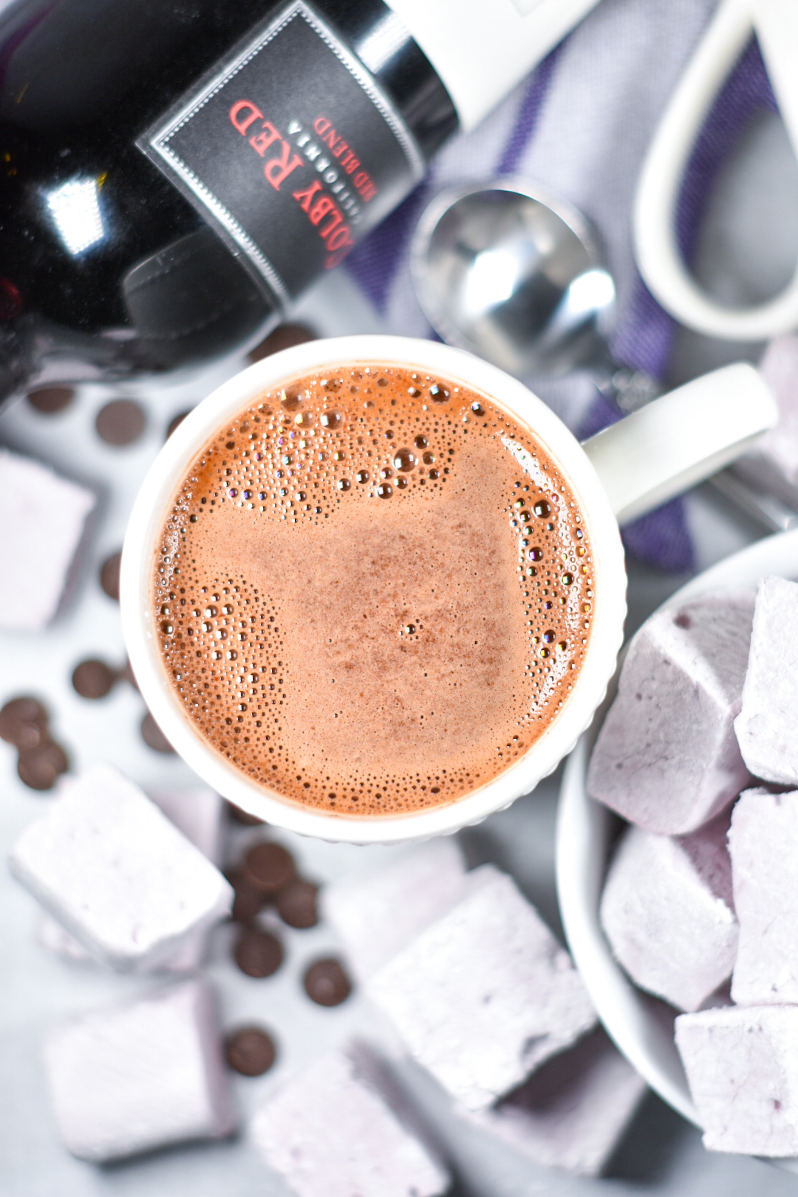 a mug of hot chocolate, marshmallows, and a purple tea towel