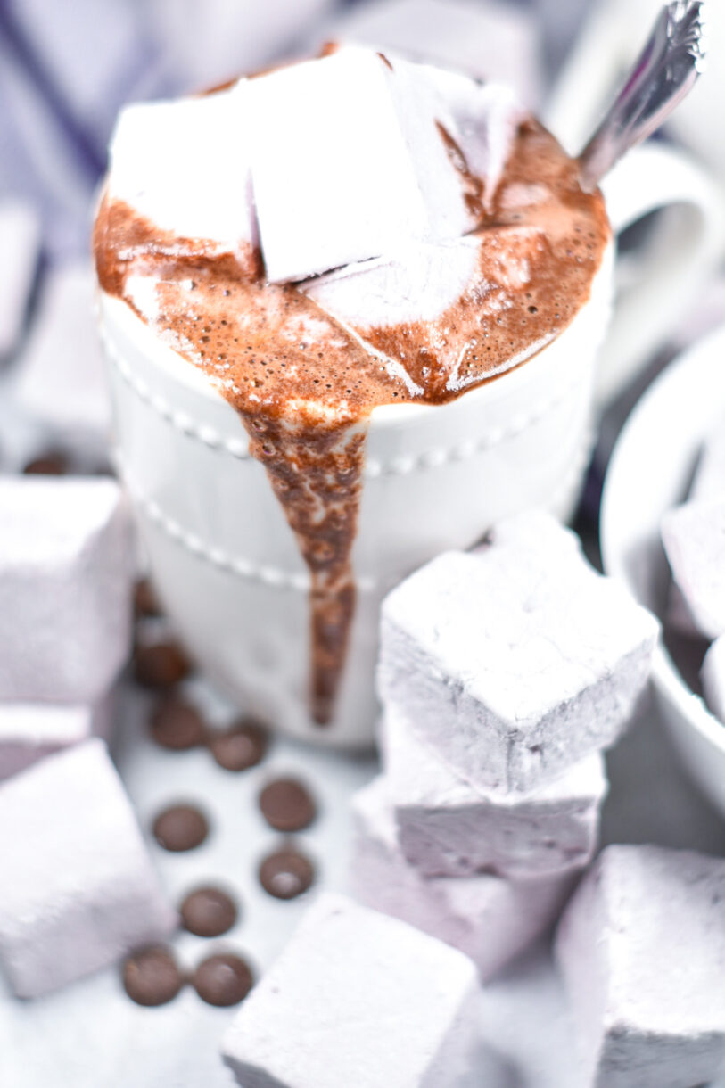 A mug of red wine hot chocolate surrounded by red wine marshmallows