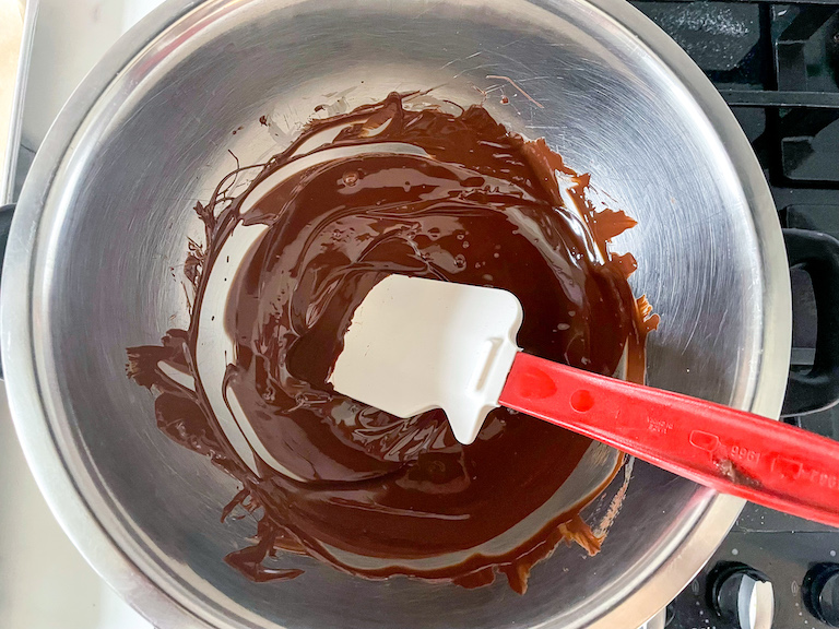 A bowl of melted dark chocolate and a spatula