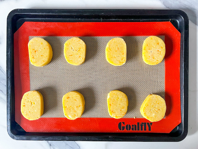 Unbaked slices of orange shortbread on a tray