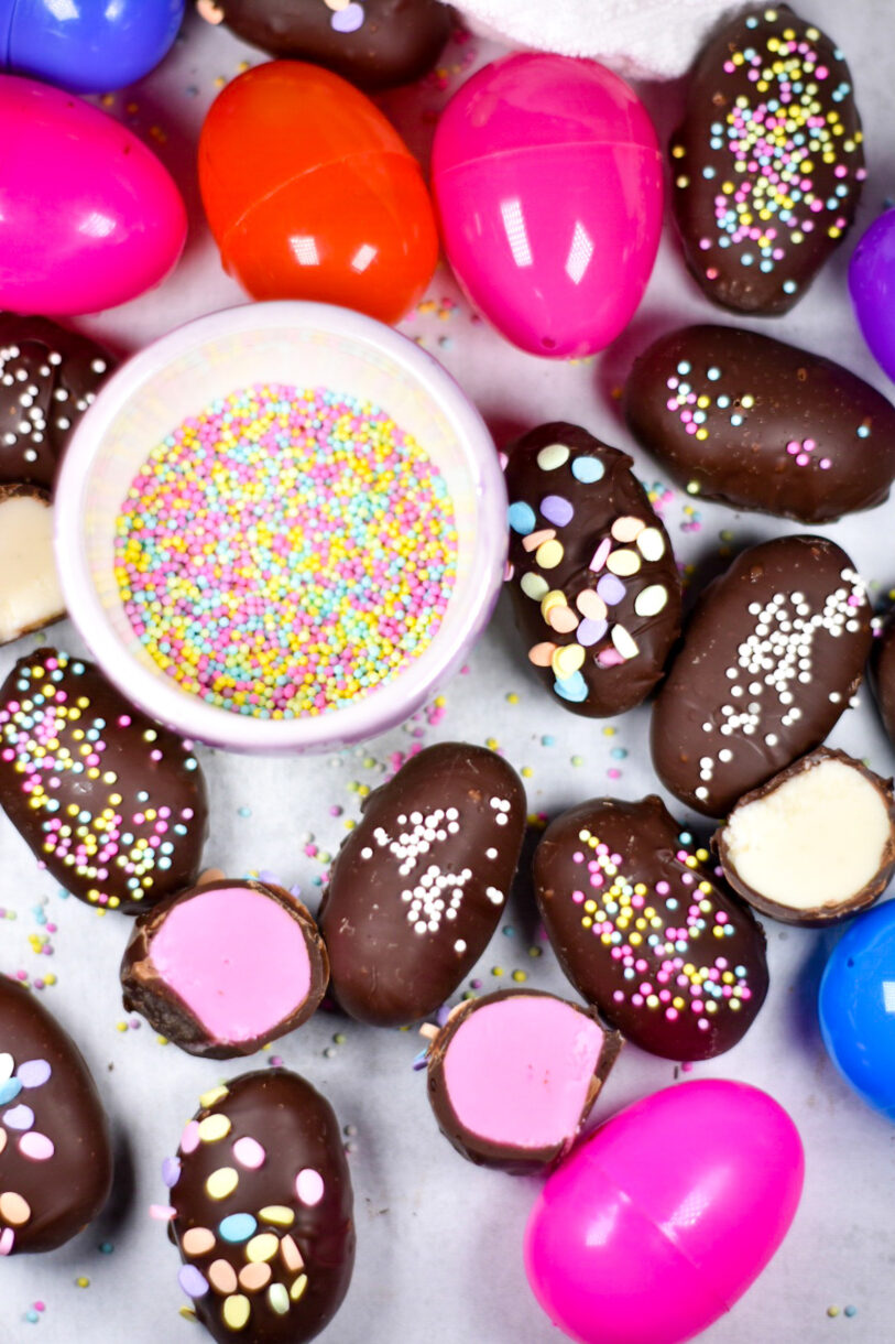 Homemade chocolate Easter eggs with plastic egg decorations and a bowl of pastel sprinkles