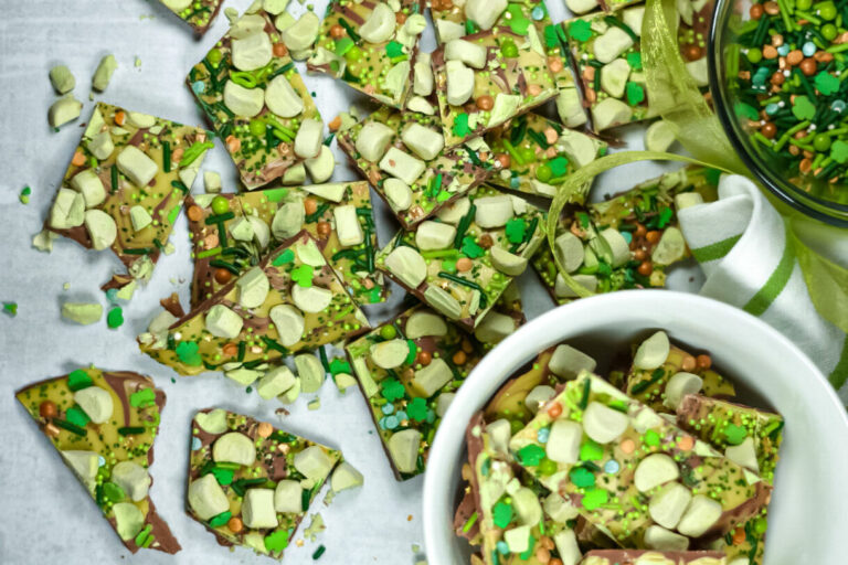 Green peppermint bark, a white bowl, and bowl of sprinkles on white background