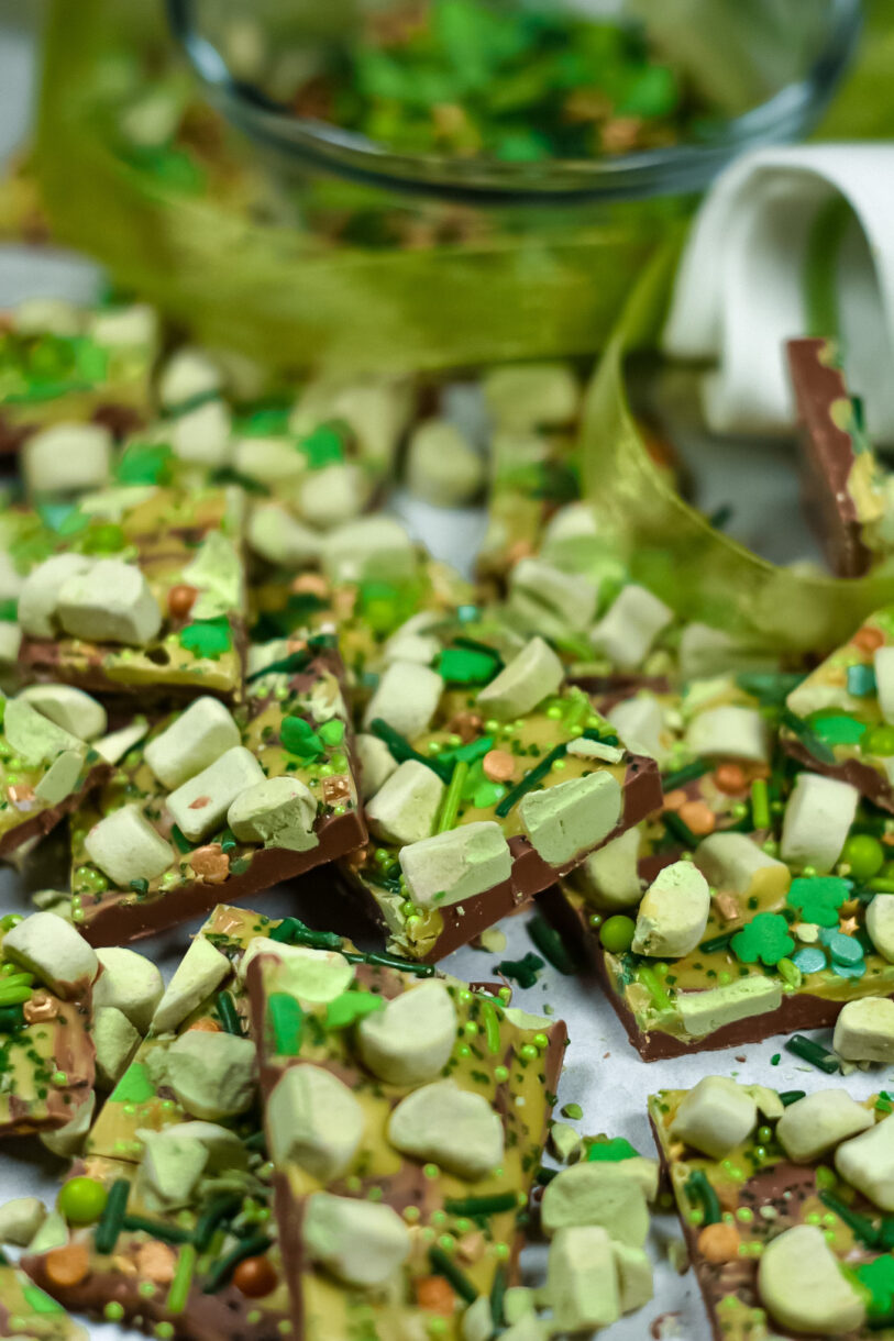 Chocolate bark and green ribbon scattered on a white surface