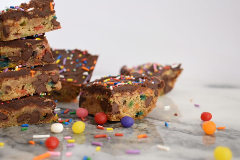 Chocolate chip confetti bars with milk chocolate frosting, on a marble surface