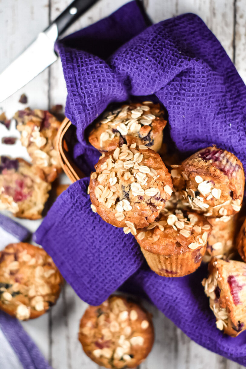 Oat and cornmeal muffins with berries in a basket with purple towel