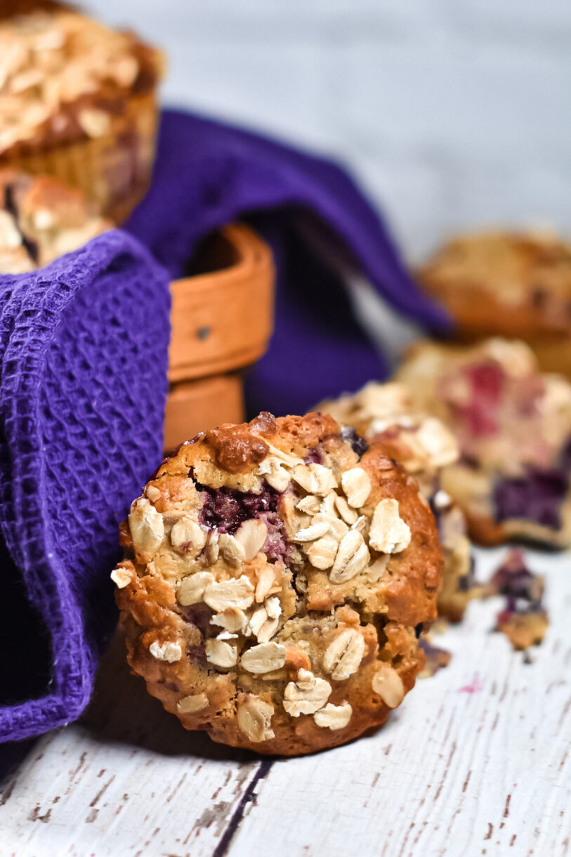 Oat and cornmeal muffins with berries, a basket, and purple tea towel