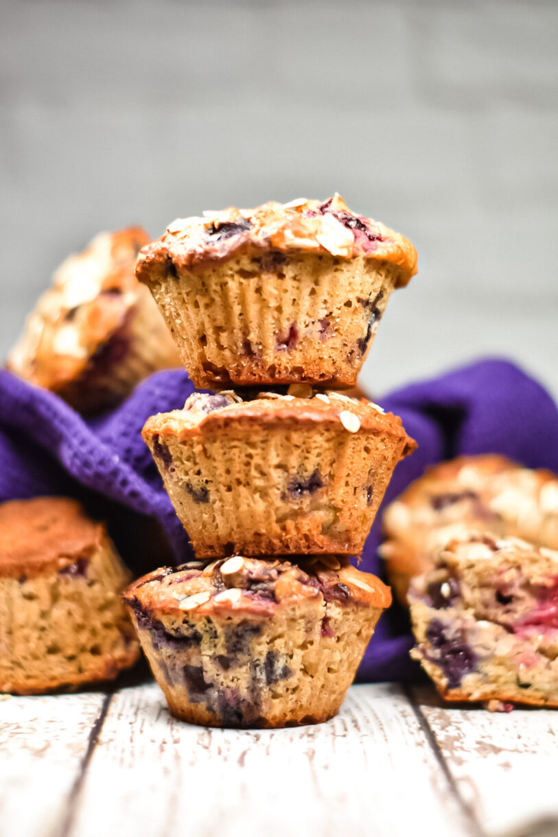 Berry muffins with oatmeal, in a stack of three on wood surface