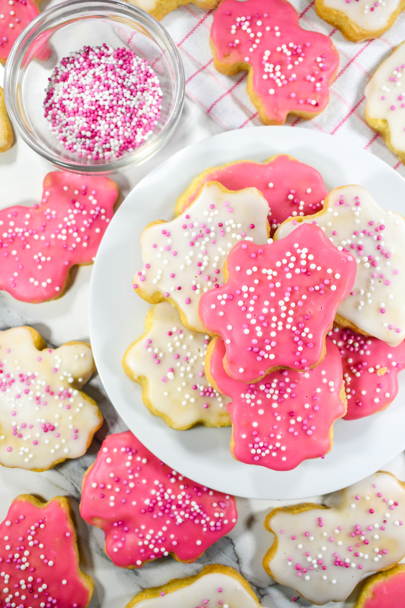 Homemade animal cookies on a plate, next to a bowl of sprinkles