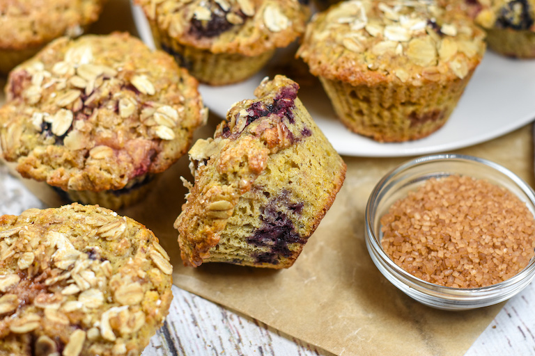 A berry muffin on its side next to a bowl of Demerara sugar