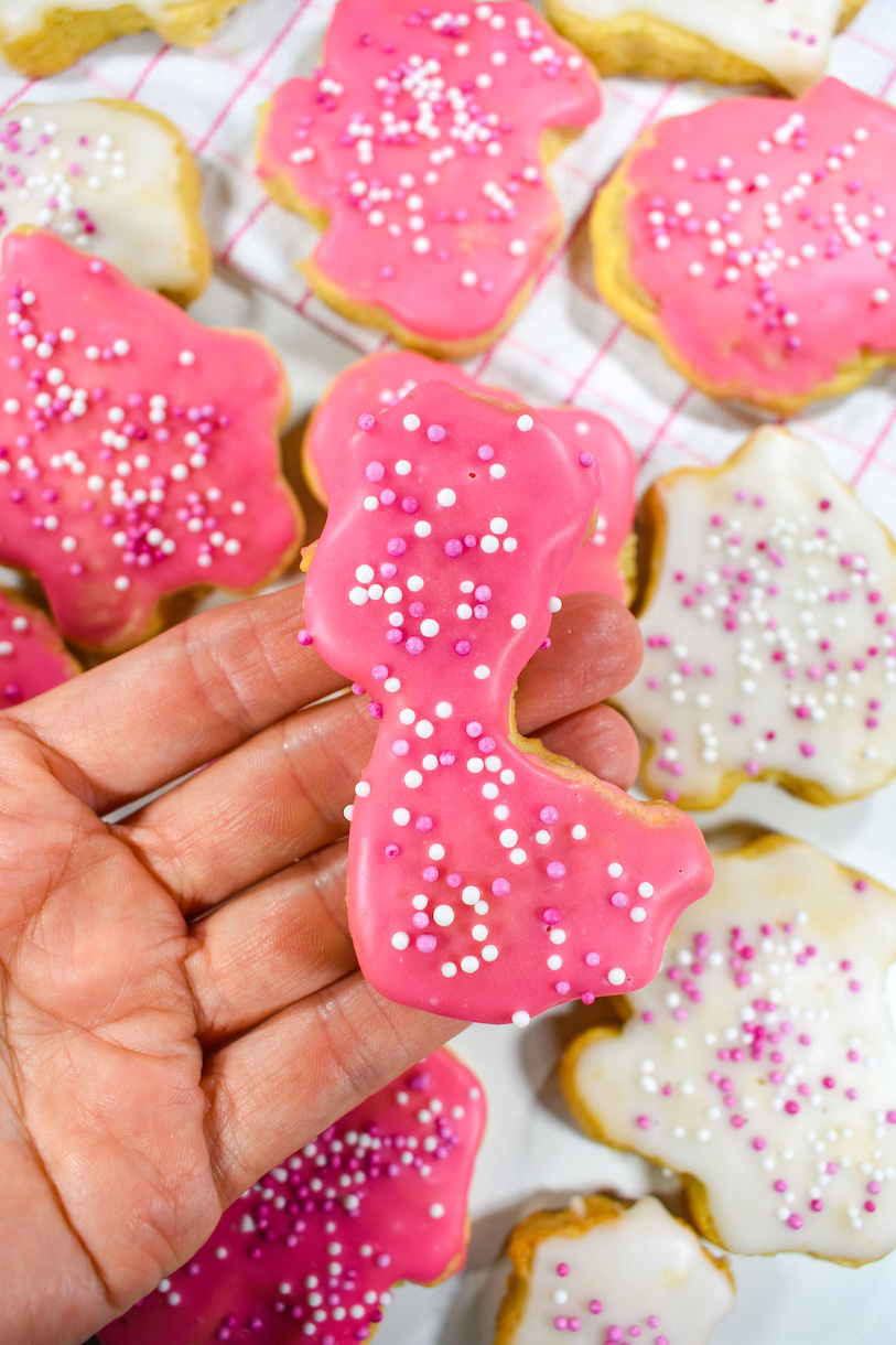 Hand holding a pink homemade animal cookie shaped like a giraffe