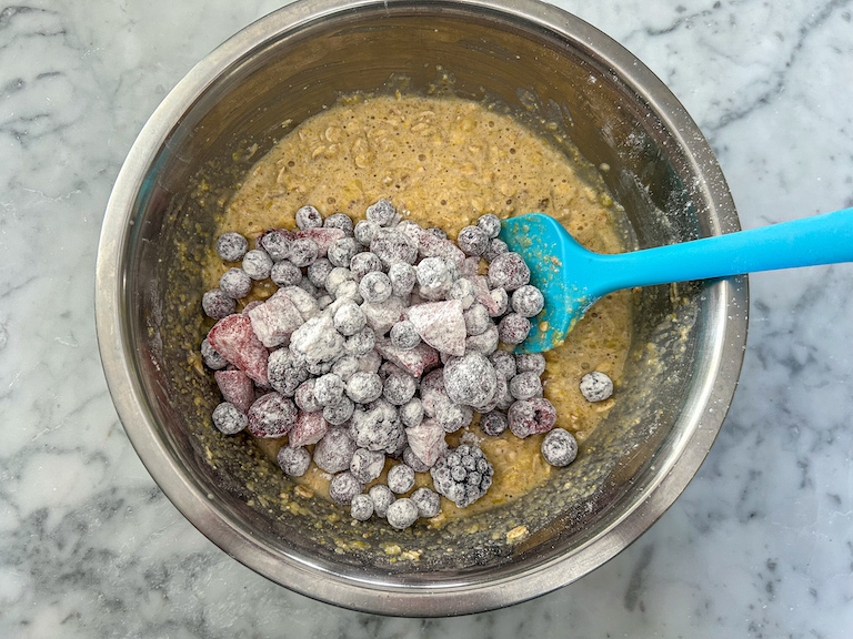 Adding flour coated mixed berries to muffin batter