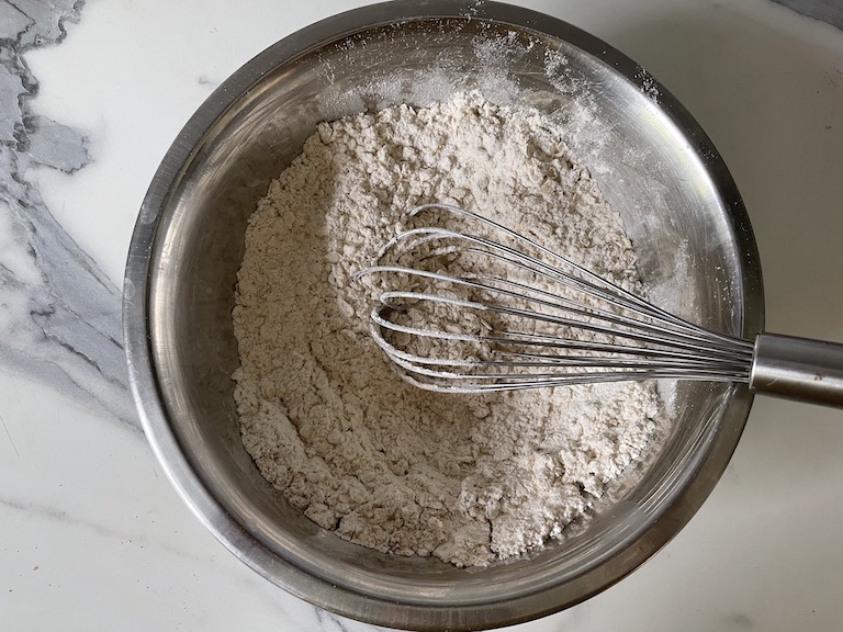 Dry cookie ingredients in a bowl with a whisk