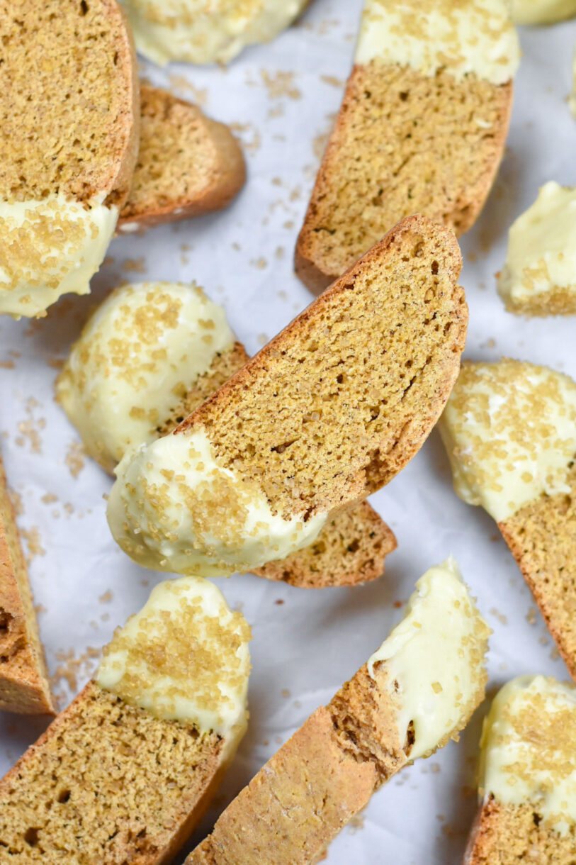 Pumpkin spice biscotti dipped in white chocolate, on white surface