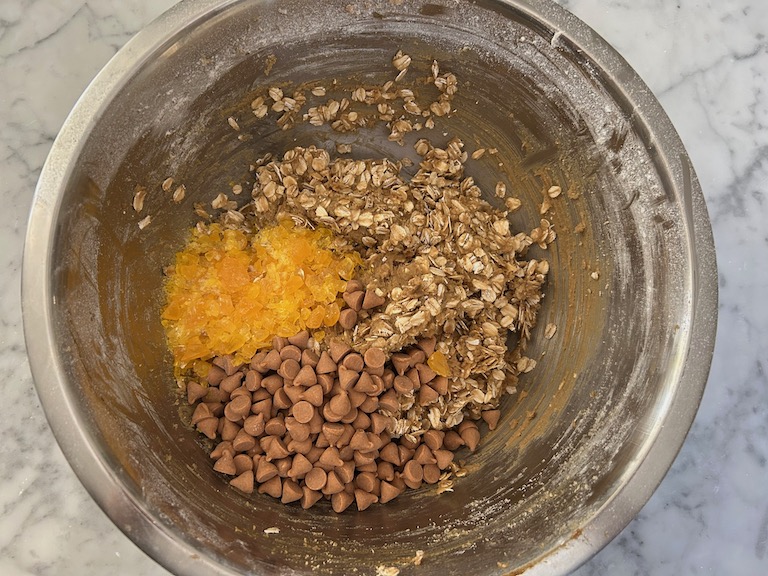 Mixing butterscotch chips and candy into oatmeal cookie dough