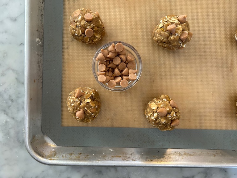 Balls of cookie dough and a dish of butterscotch chips