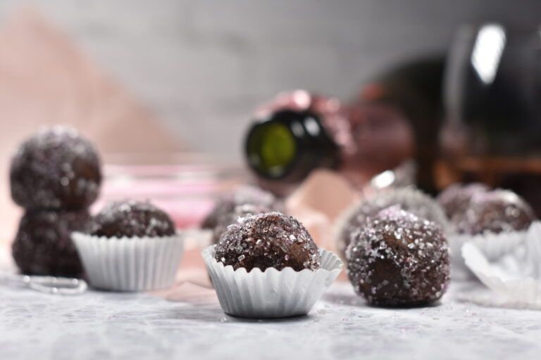 Sparkling Rosé Truffles in truffle cups, on a white surface