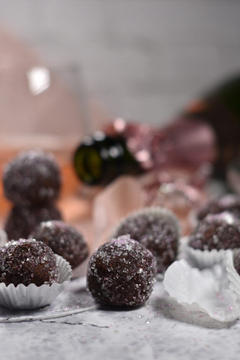 Sparkling Rosé Truffles in white truffle cups, with a glass of wine and open bottle