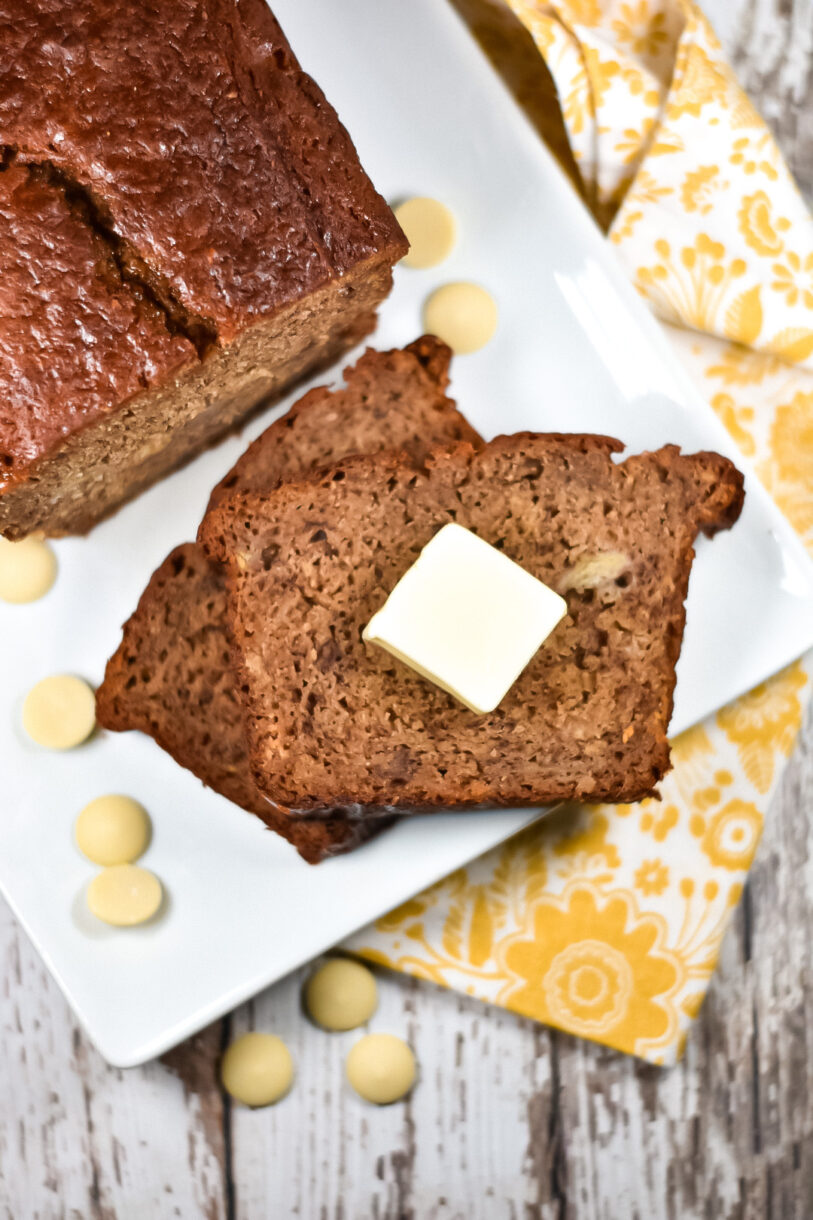 Loaf of chai spiced banana bread and slices with butter on white plate