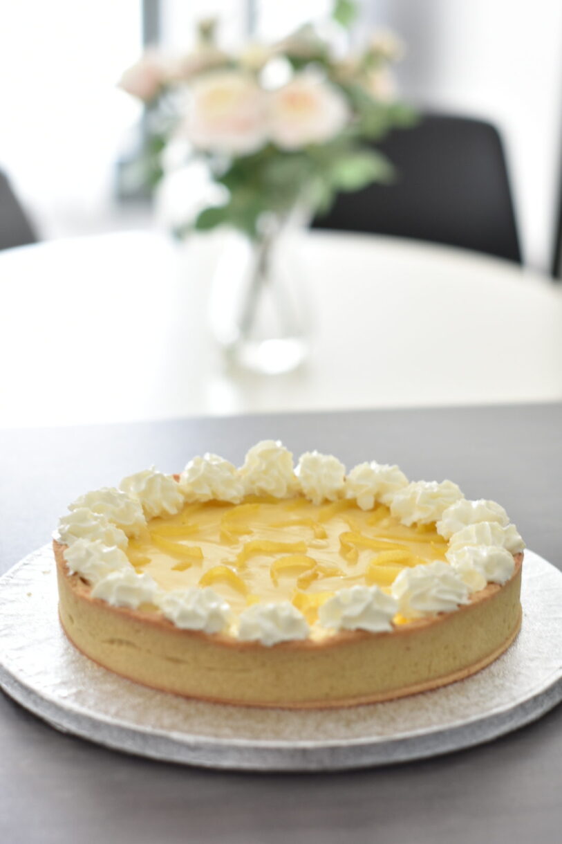Lemon tart on a table with flowers in background