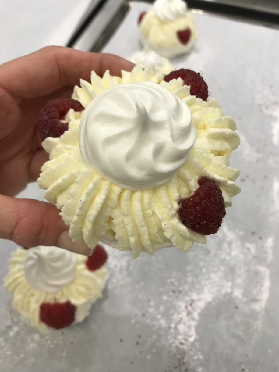 Hand holding a meringue nest with raspberries