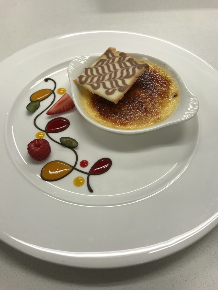 Creme brulee plating white chocolate piping and fruit puree