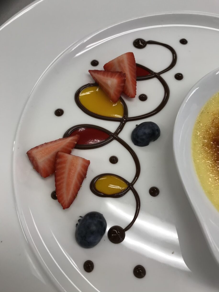 Chocolate piping and fruit coulis on white plate