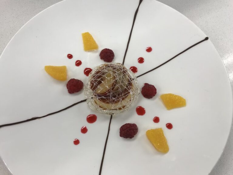 My finished creme caramel, plated on a white plate with fruit coulis and chocolate piping