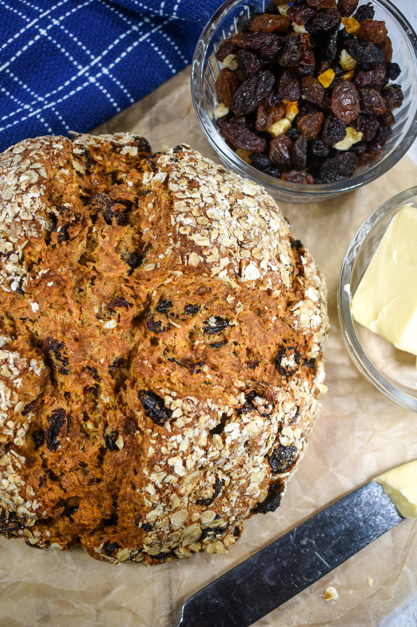 Loaf of Irish soda bread, dish of dried fruit, butter, and blue towel