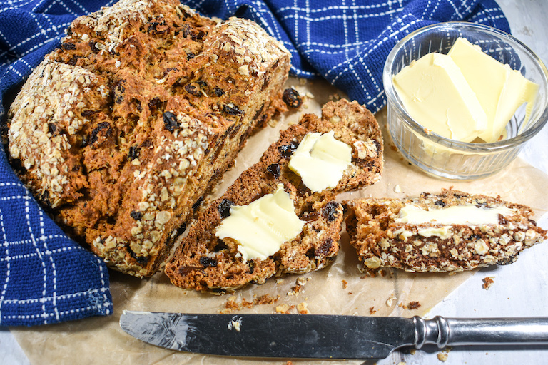 Sliced Irish soda bread with butter, butter knife, and tea towel