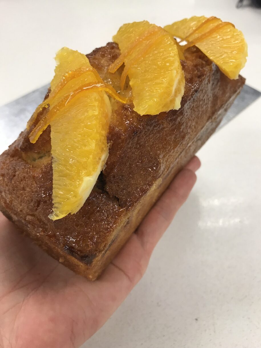 Hand holding a loaf of orange chocolate marble cake
