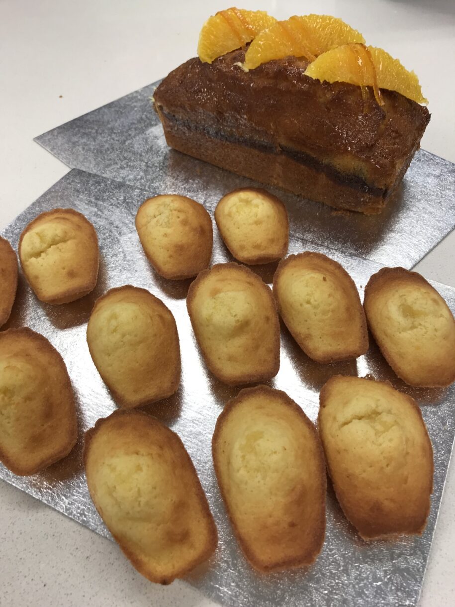 Madeleines and orange loaf cake on silver boards