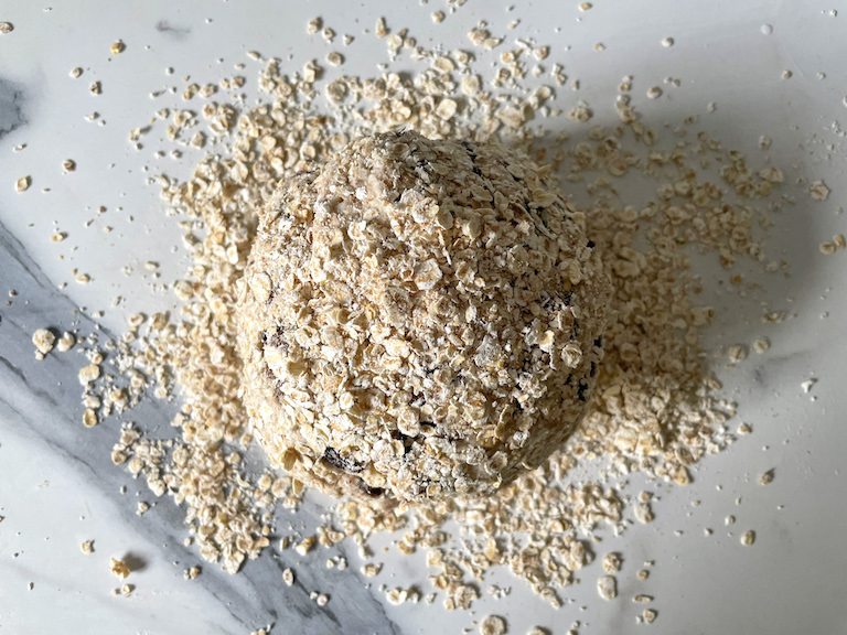 A ball of soda bread dough on a marble countertop surrounded by oats