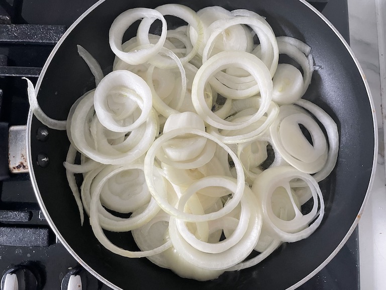 Raw onion rings in a saucepan on the stovetop